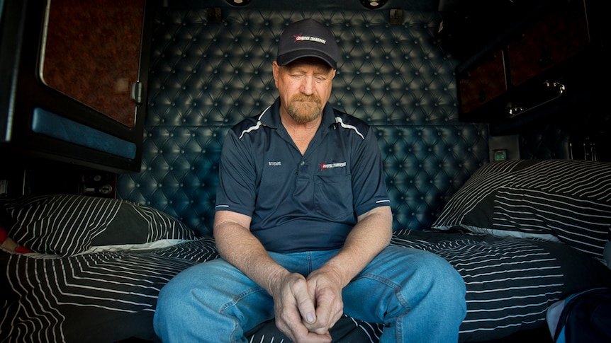 A man rests in a truck cabin.
