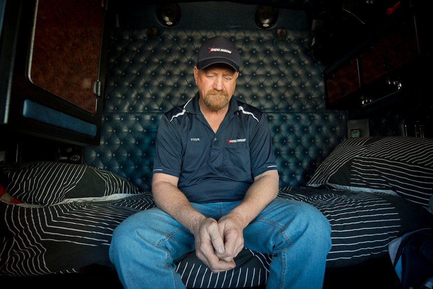 A man rests in a truck cabin.