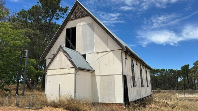 Un edificio alto con un techo empinado y al que le faltan algunos paneles de fibra. 