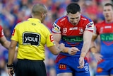 An NRL player points at his arm, telling the referee he was bitten