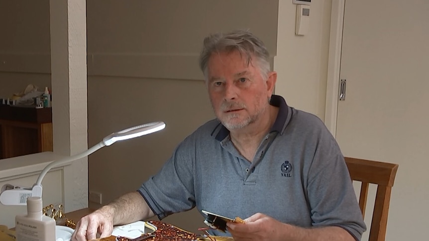 A Caucasian man with a beard, building a guitar at home. 