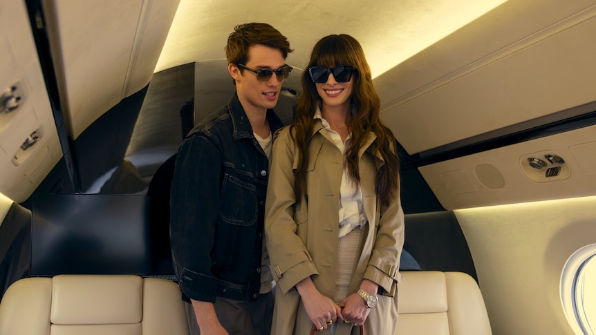 A film still of Nicholas Galitzine, 29, and Anne Hathaway, 41, who is smiling brightly. They're boarding a private plane.