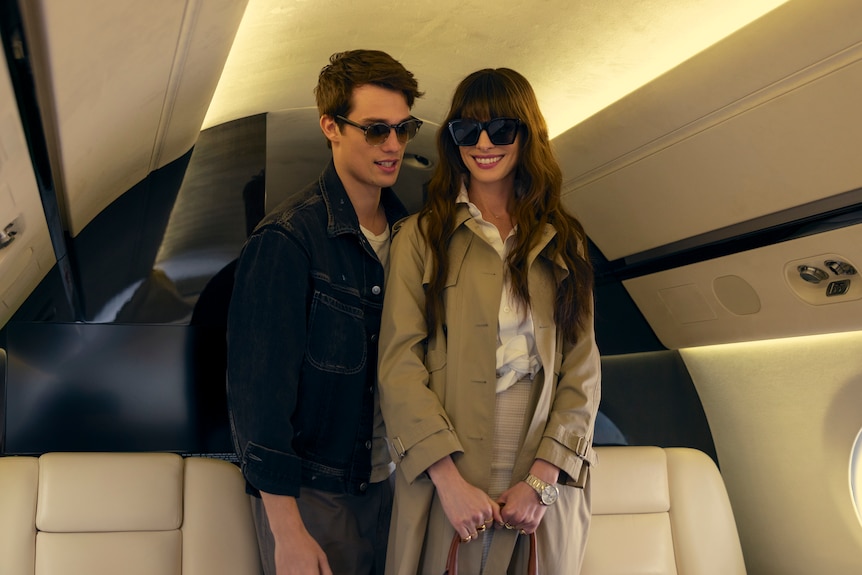 A film still of Nicholas Galitzine, 29, and Anne Hathaway, 41, who is smiling brightly. They're boarding a private plane.