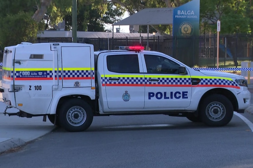 A police car parked outside Balga Primary School, which is surrounded by police tape.