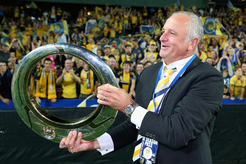 Glory at last ... Mariners coach Graham Arnold celebrates with the fans, trophy in hand.