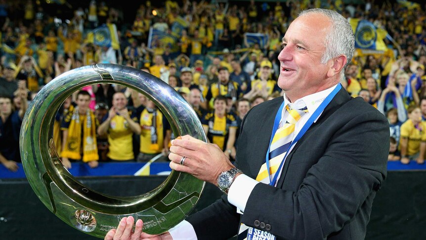 Glory at last ... Mariners coach Graham Arnold celebrates with the fans, trophy in hand.