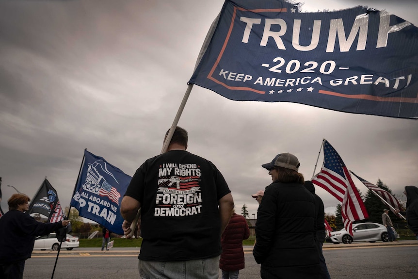 A man holding a Trump campaign flag