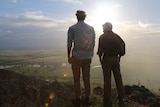 Two men stand on cliff looking out