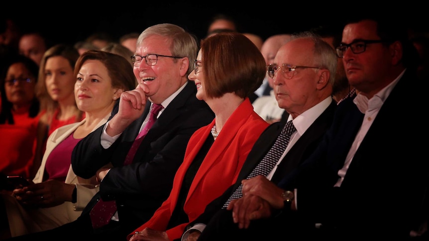 Julia Gillard looks at Kevin Rudd both laughing in the front row and look towards the stage. Paul Keating isn't smiling.