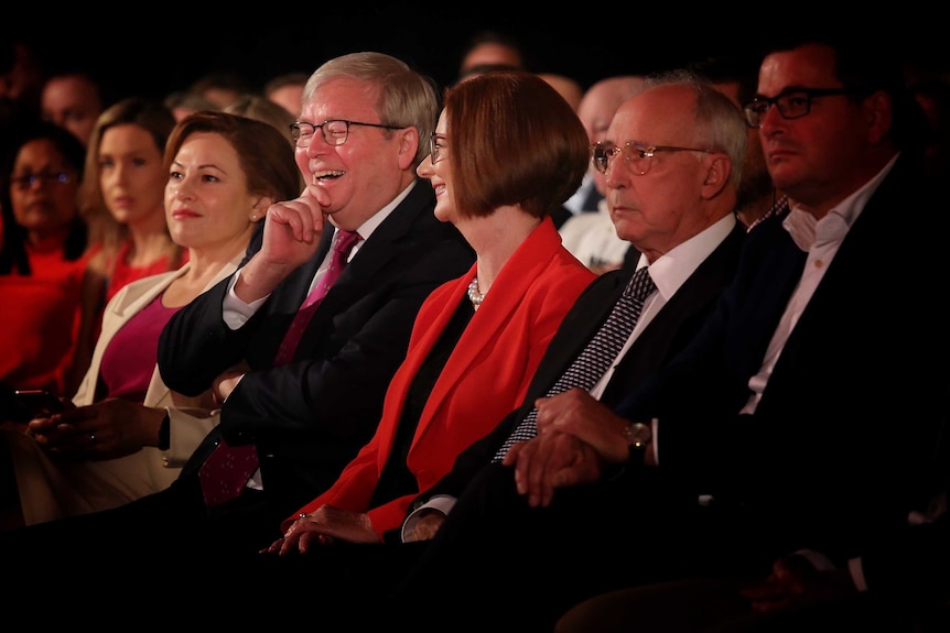 Julia Gillard looks at Kevin Rudd both laughing in the front row and look towards the stage. Paul Keating isn't smiling.