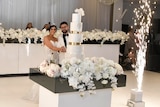 Venitta Issa and Craig Lamrock cut the cake at their wedding reception as fireworks explode next to them.