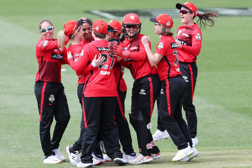 The Melbourne Renegades gather to hug and celebrate on the cricket pitch.