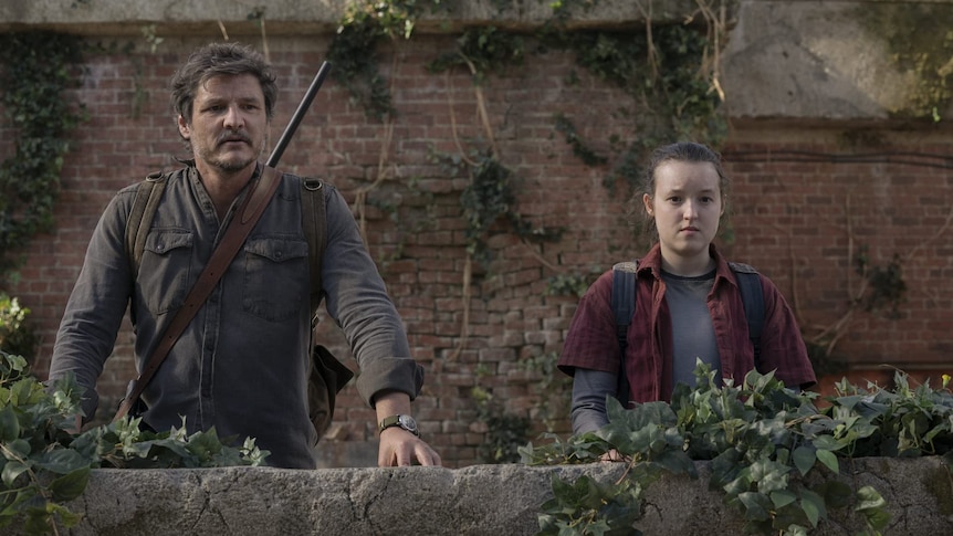 Joel and Ellie from the HBO The Last of Us stand on a balcony side by side.