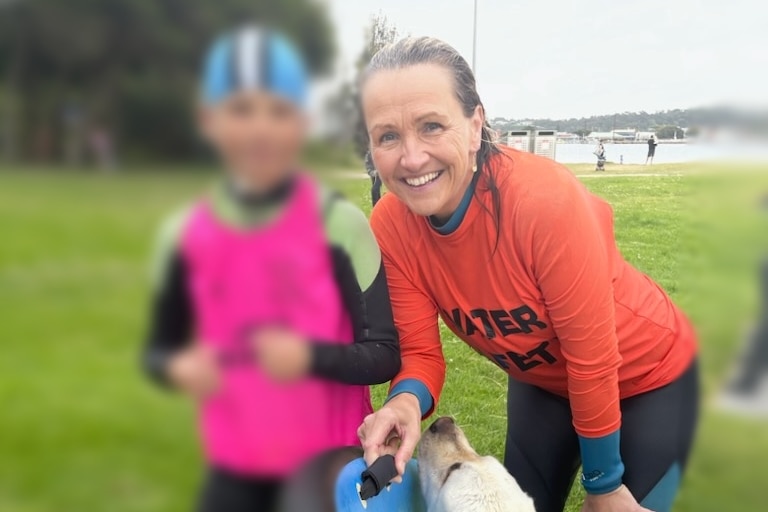 Foster carer Sophie Brown smiles while tugging a frisbee from her dog's mouth, standing next to her primary school-aged son.