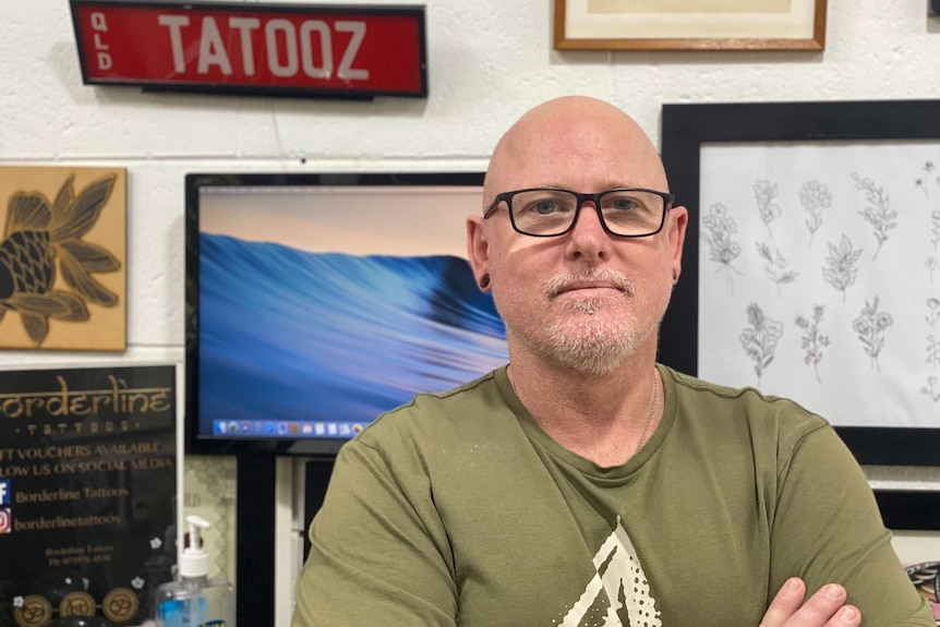 A man stands behind art at a tattoo shop