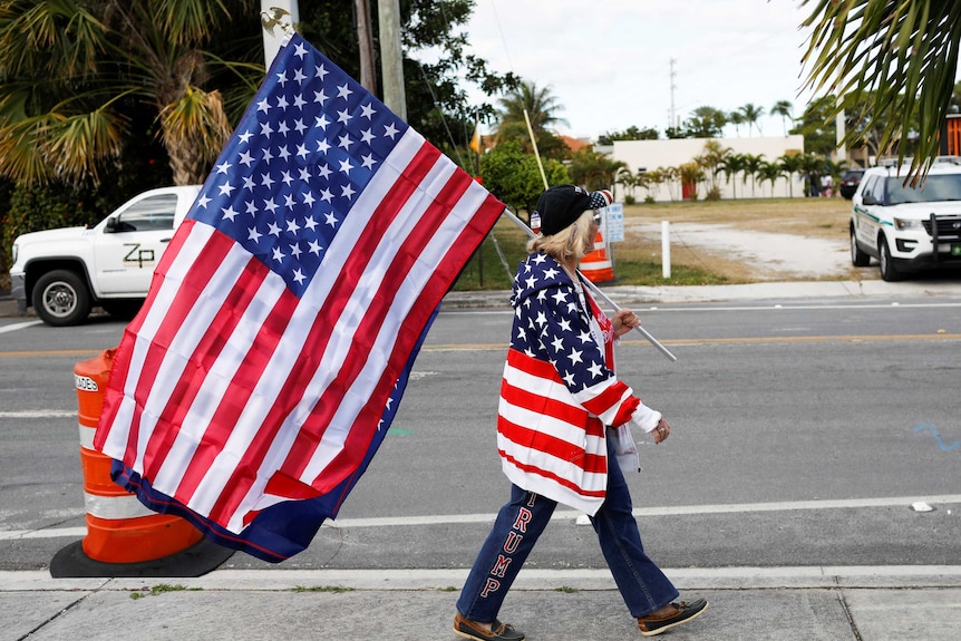 A Trump supporter walks with a US flag