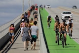 People walking and cycling over a bridge