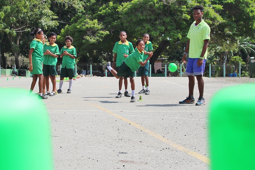 School students practice bowling. Shot is taken from between the stumps the bowler in the distance