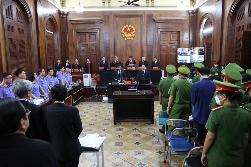 A court room in Vietnam filled with court officials and people in military uniforms.