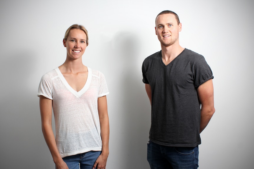 Emma and David McKeon stand against a white wall, smiling.