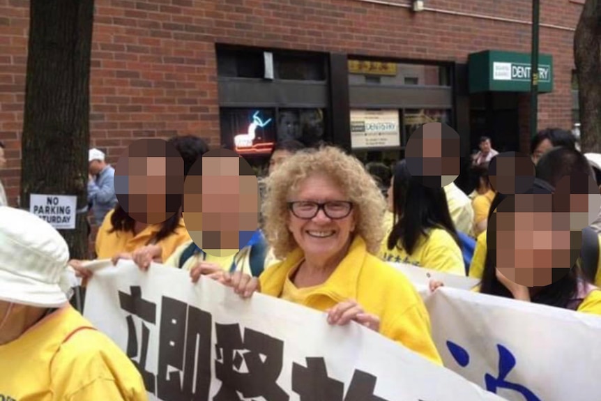 Colleen holds a banner with other Falun Gong members.