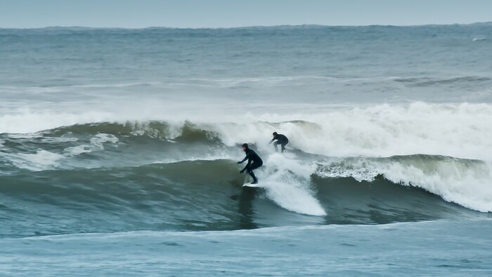 A couple of people riding waves on surfboards.