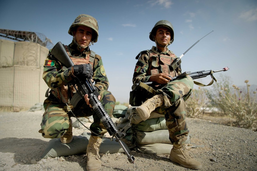 Two Afghan soldier sit and hold guns.