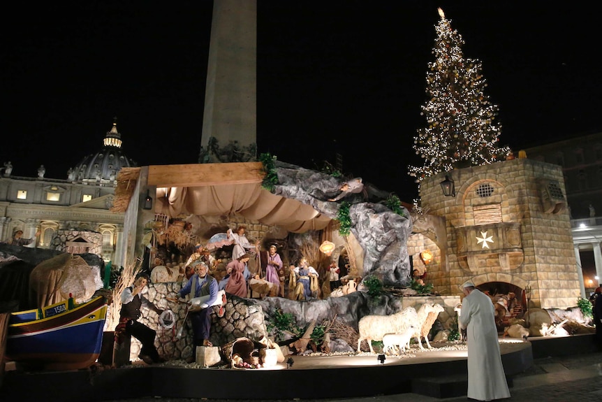 Pope Francis prays in front of a nativity scene in St Peter's Square, after celebrating a New Year's Eve vespers mass.