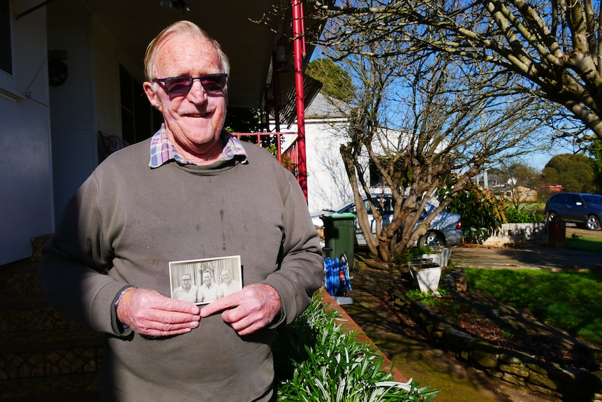 A man holds an old photograph.