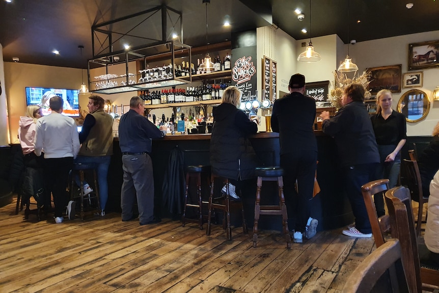 A bunch of people standing at a bar.