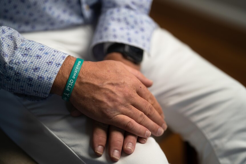A man wearing a bracelet with PTSD awareness written on it