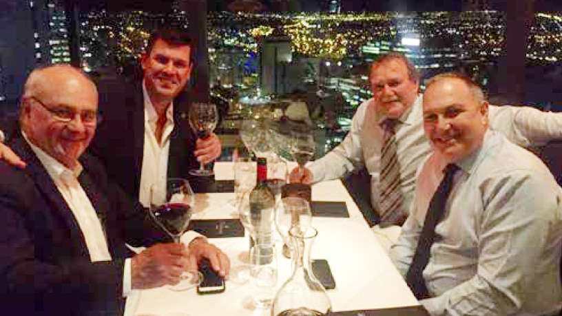 Four men dine at a restaurant in a city skyscraper