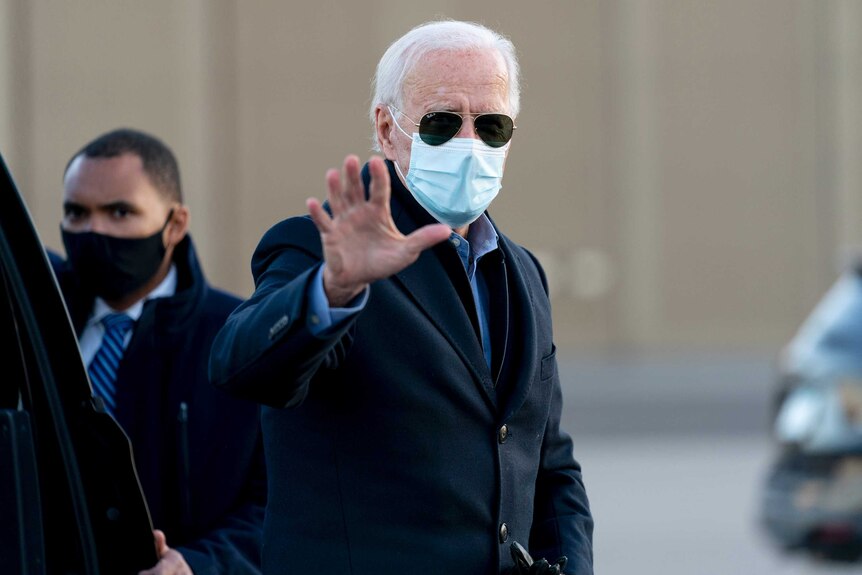 Joe Biden waves at the camera while wearing sunglasses and a mask during an election campaign event in Minneapolis.