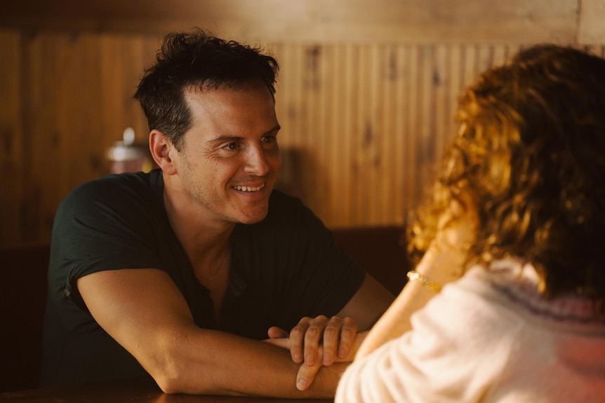 A film still of Andrew Scott and Claire Foy. Scott is smiling, only the back of Foy's head can be seen.