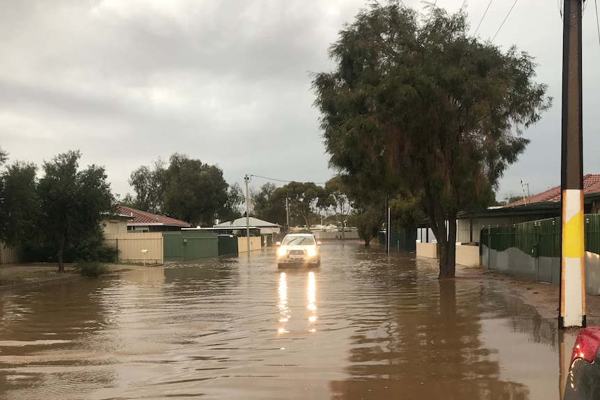 A four-wheel drive drives down a street covered in brown wate