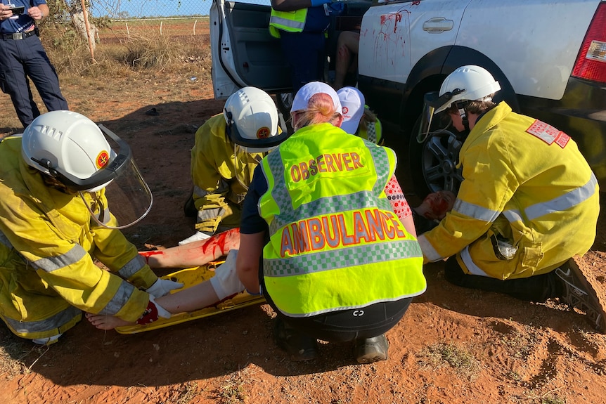 Volunteers in high vis load a woman on a stretcher