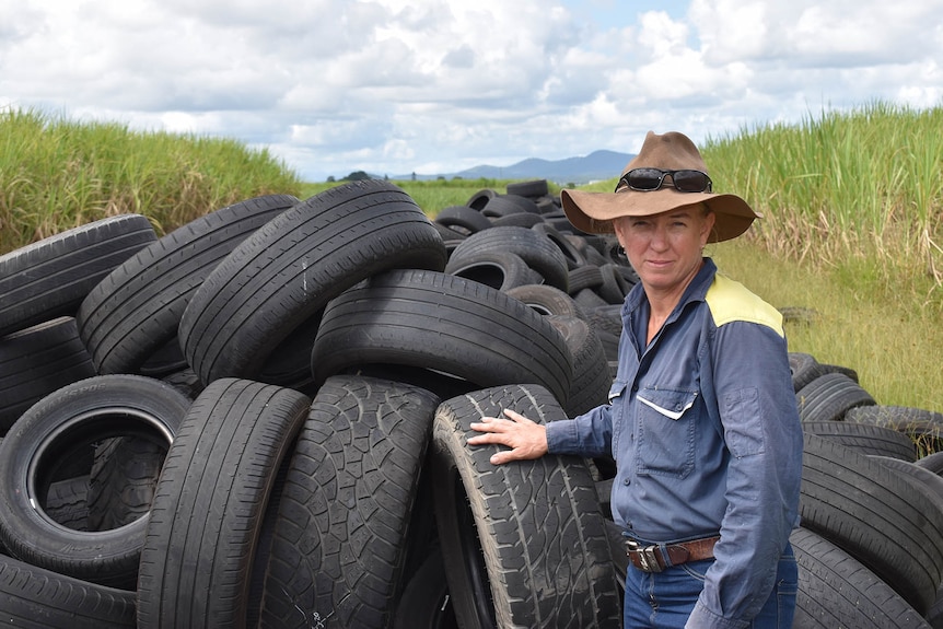 Gold Coast farmer stands in front of a large pile of illegally dumped tyres.