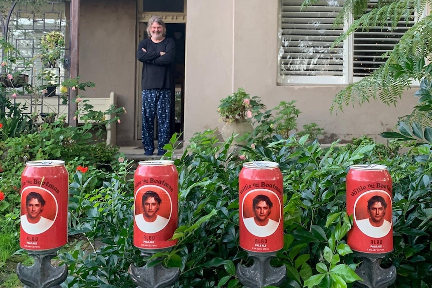A line of red cans showing Anthony Albanese's face, on a fence.