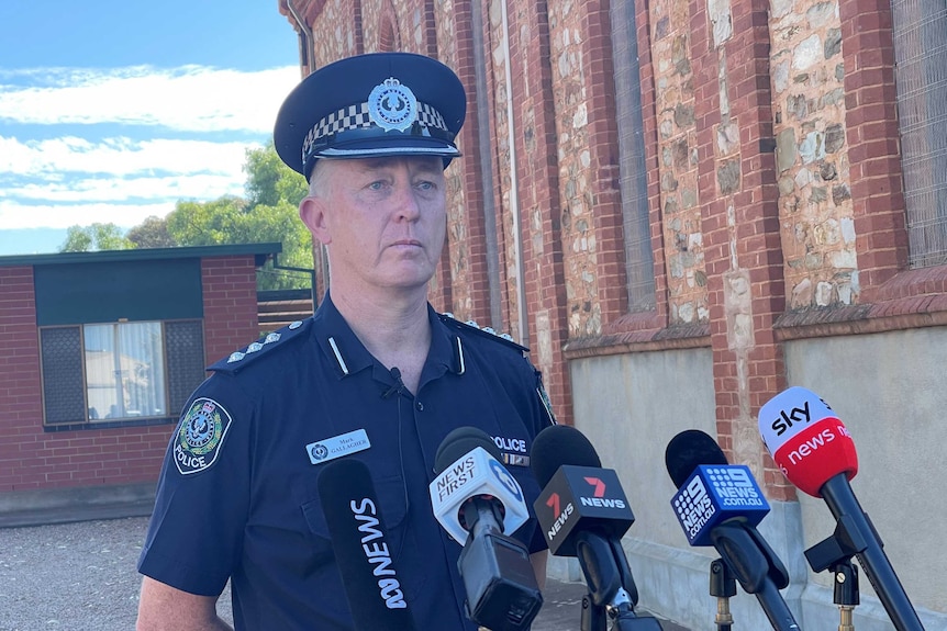 A police officer stands in front of microphones