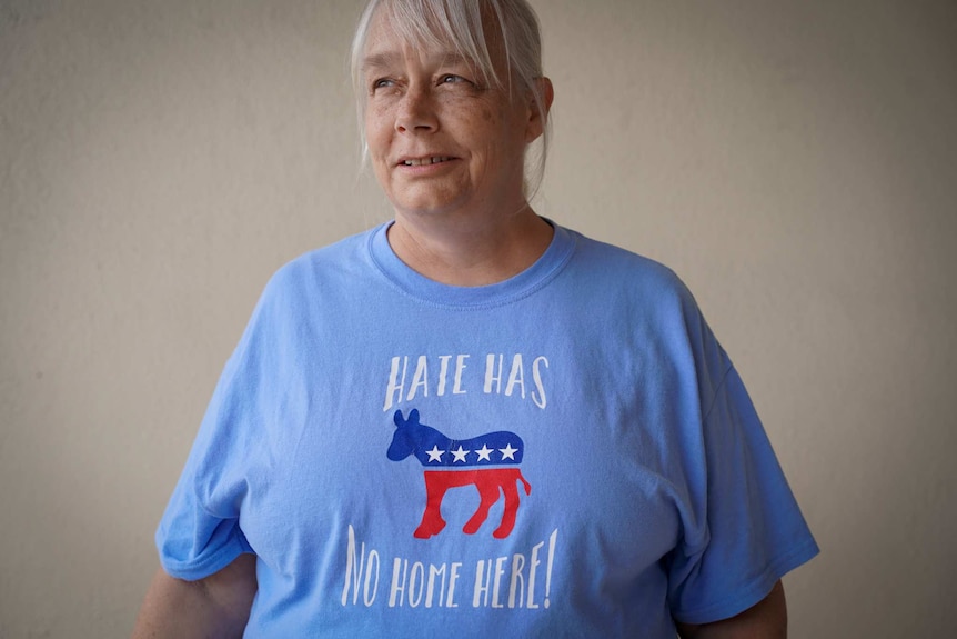 A woman with grey hair in a t-shirt reading "hate has no home here!'
