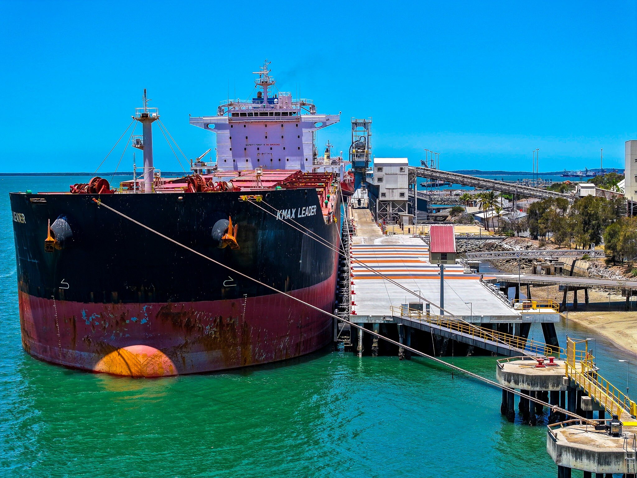 Large red and black ship next to a port.