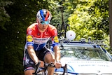 A professional cyclist is seen riding on his bike ahead of the team car.