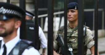 A soldier stands behind the railings as a police officer stands in front in Downing Street.