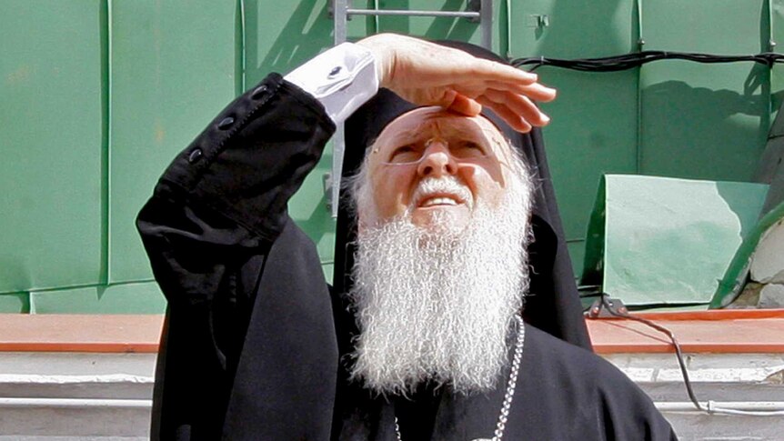 Patriarch Bartholomew I squints as he looks up into the sky