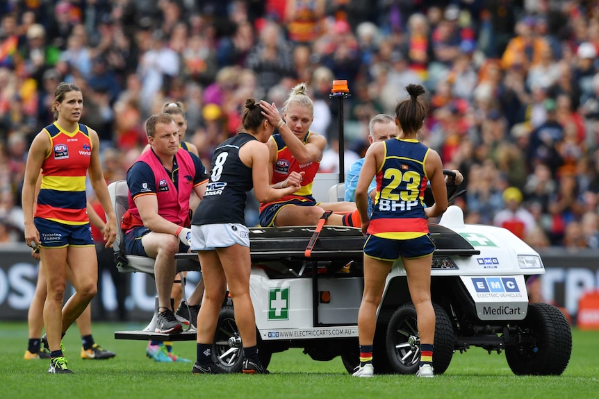 Erin Phillips hugging a Carlton player after being taken off Adelaide Oval after sustaining a knee injury.