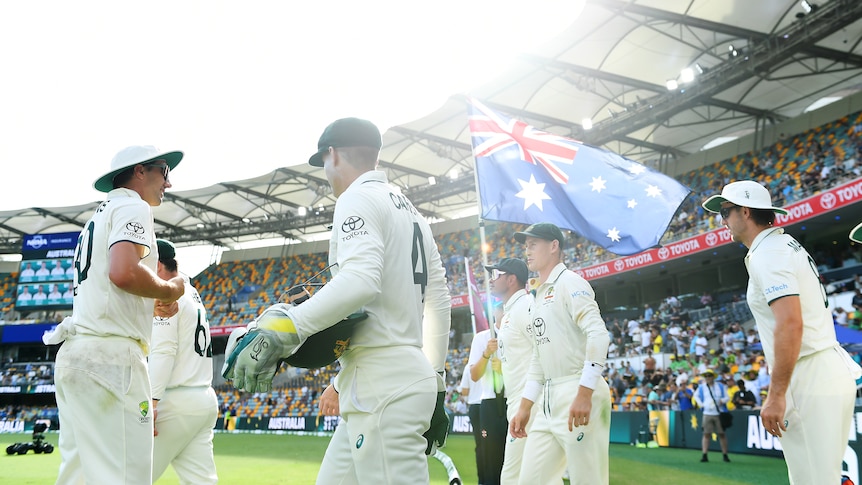 Australian players walk on the field next to an Australian flag
