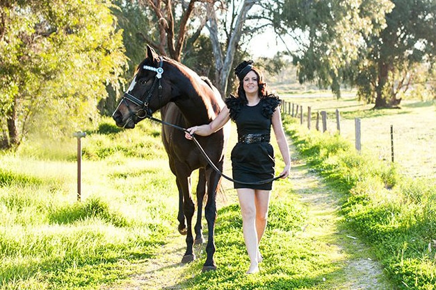 Hana Dickson walks through a paddock with a horse