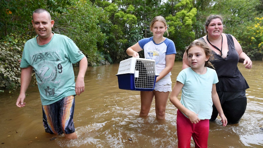 Family wading through floodwaters with cat