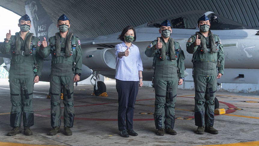 Taiwan's President Tsai Ing-wen stands in front of a military plane with soldiers.