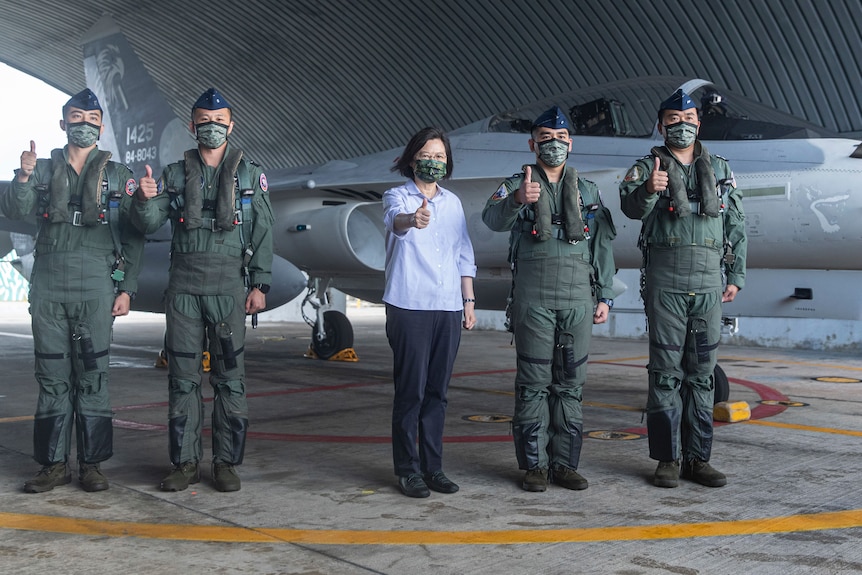 Taiwan's President Tsai Ing-wen stands in front of a military plane with soldiers.